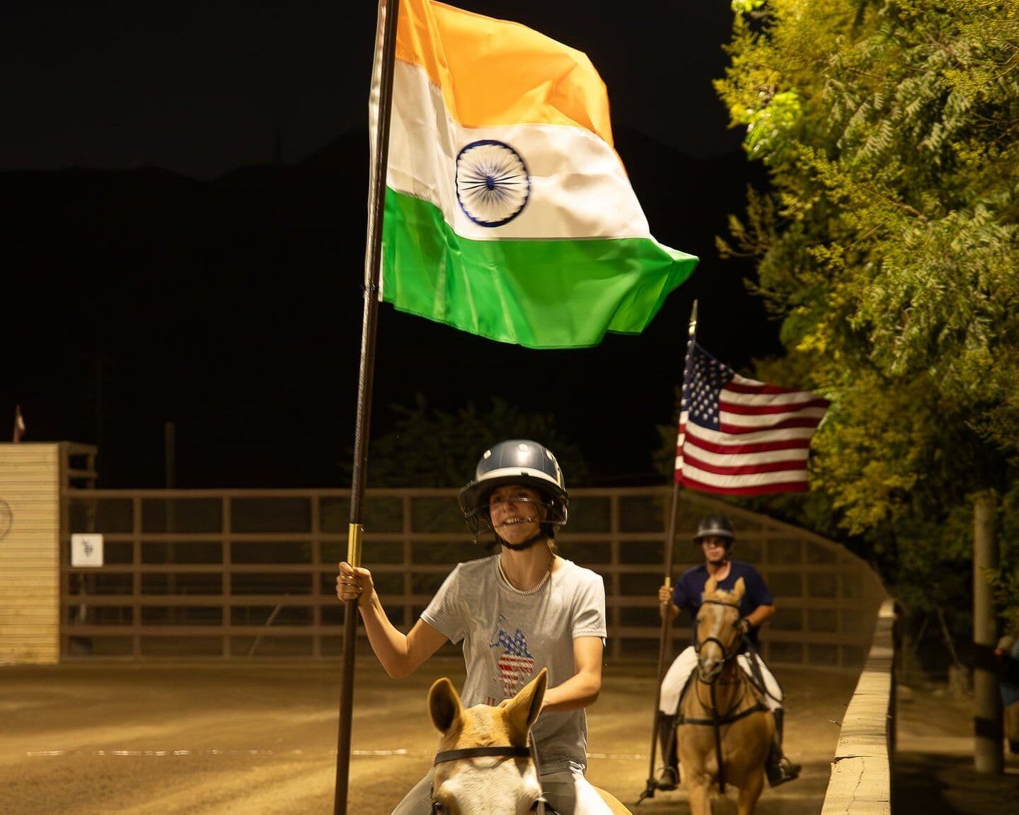 Riders carry the Indian and American flags into the arena at night