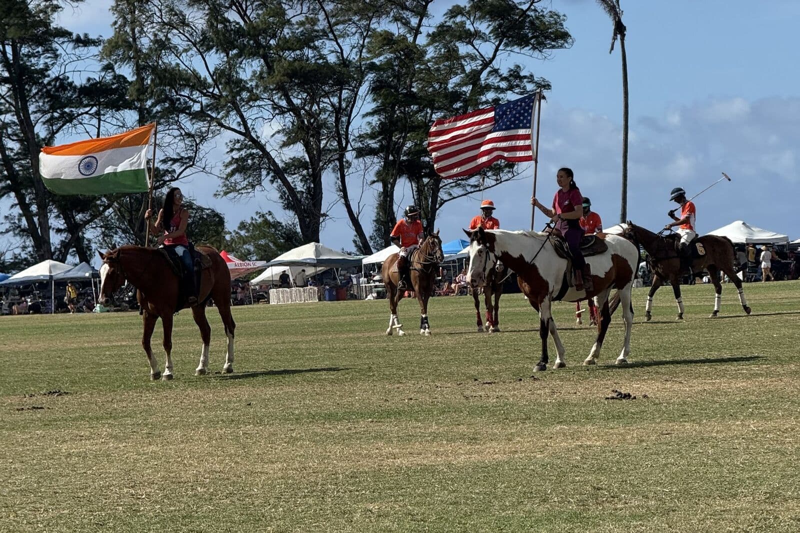 Riders with the Indian and American flags on a grass polo field in Hawaii