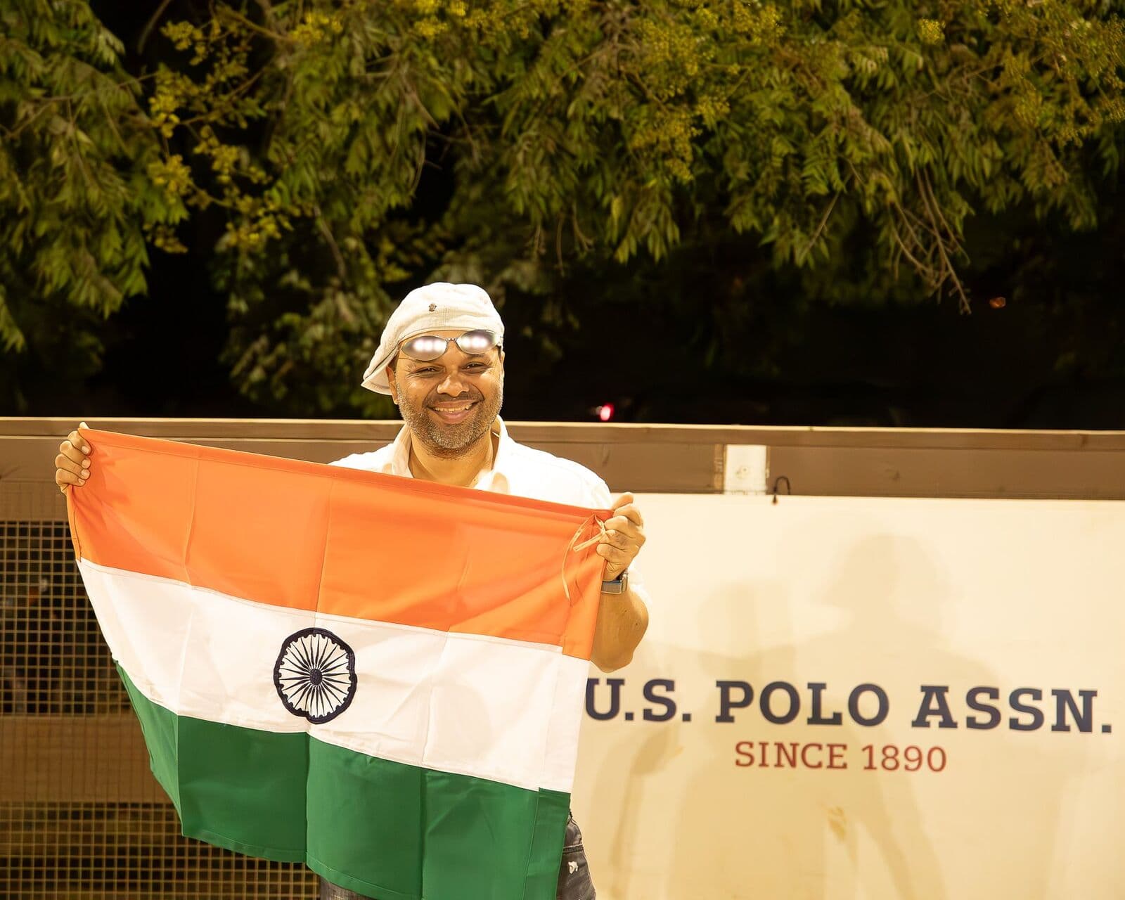 Chaitania R. Kumar holding the Indian flag in front of a U.S. Polo Assn. banner